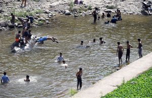 A large number of people, including children and youngsters, cool off by swimming and playing in Korang Nullah, as an intense heat wave continues to grip the region driving residents to seek refuge in natural water bodies.
