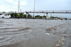 Vehicles passing through rainwater accumulated at IJP Road during heavy rain in the Federal Capital.
