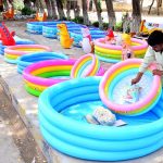 A vendor arranges colourful inflatable swimming pools for sale along a roadside to attract the customers at Thandi sarak