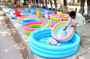 A vendor arranges colourful inflatable swimming pools for sale along a roadside to attract the customers at Thandi sarak