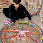 A worker busy in coloring donkey cart wheels at his workplace