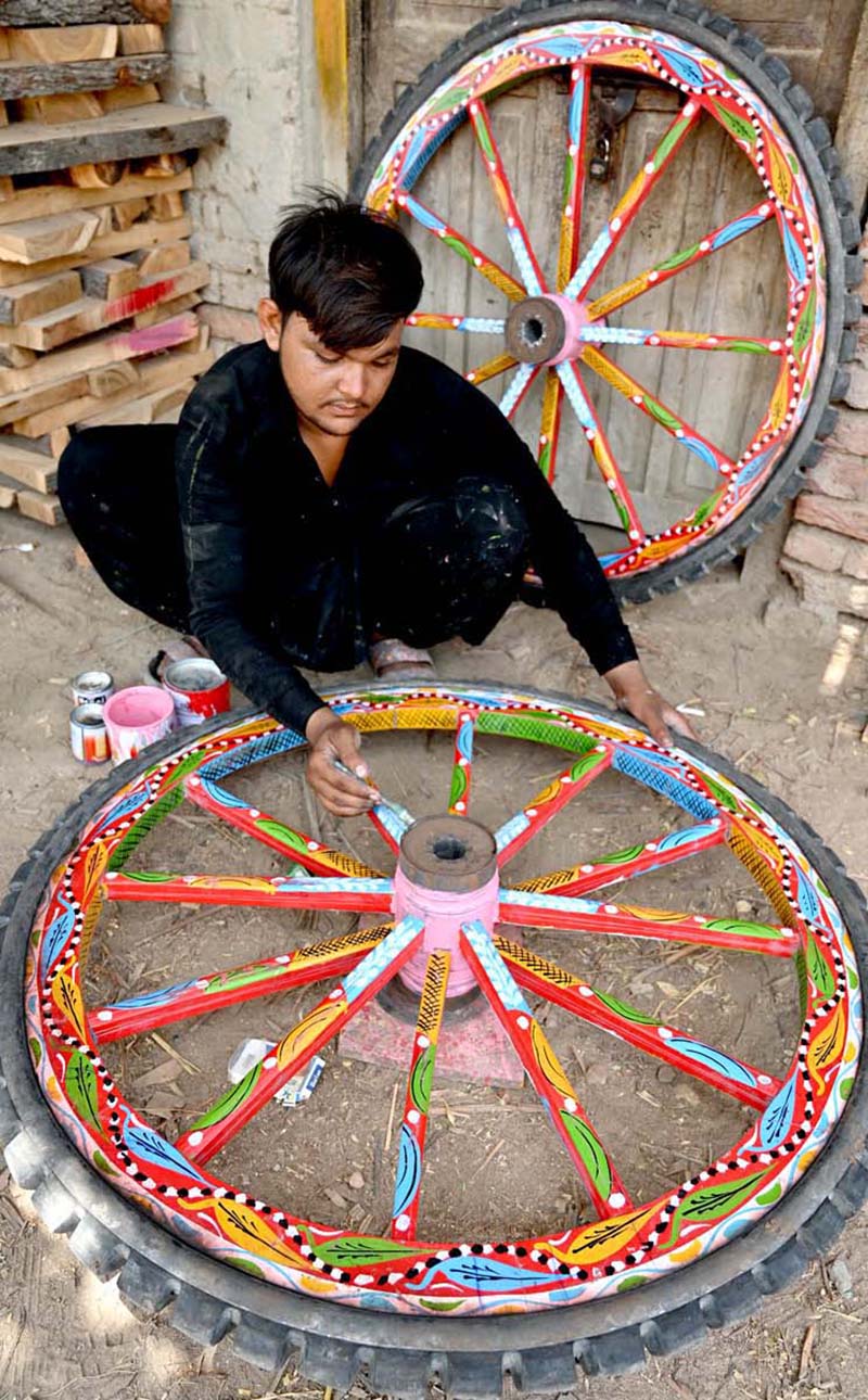 A worker busy in coloring donkey cart wheels at his workplace