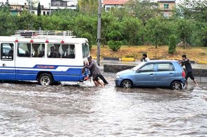 Vehicles passing through rainwater accumulated at IJP Road during heavy rain in the Federal Capital.