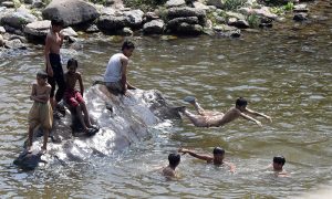 Youngsters dive and swim in Korang Nullah to seek relief from the scorching summer heat