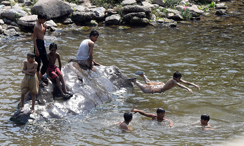 Youngsters dive and swim in Korang Nullah to seek relief from the scorching summer heat