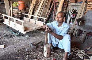 A worker busy in coloring donkey cart wheels at his workplace