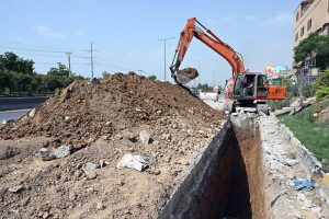 A excavator breaks through road surface during sewerage pipeline installation work on IJP Road