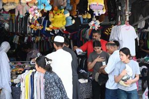 A vendor arranges a vast collection of carpets and rugs of various designs, patterns and sizes at a carpet shop in weekly bazaar H-9, Federal Capital