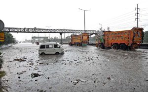 Vehicles passing through rainwater accumulated at IJP Road during heavy rain in the Federal Capital.