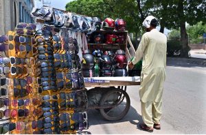 A vendor sells sunglasses and colorful helmets for bikers seeking eye protection and safety during hot weather.