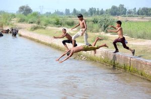 Youngsters jumping and bathing in canal to get some relief from hot weather in city.