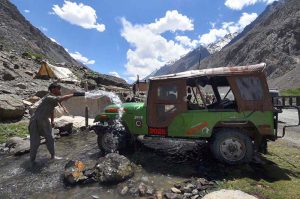 A driver is busy washing his vehicle with stream water in Upper Chitral.