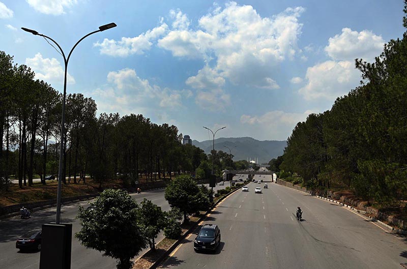 Clouds hover over the Margalla Hills as vehicles make their way along a Expressway in the Federal capital