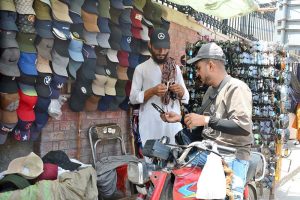 A customer is selecting sunglasses from a roadside vendor.