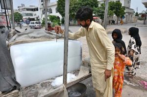 A vendor is selling ice to customers at his roadside setup as demand increased due to hot weather in the Federal Capital.