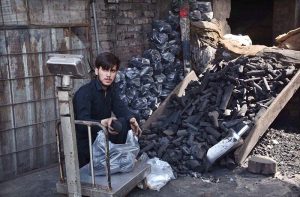 A coal vendor packs coal into plastic bags for customers.