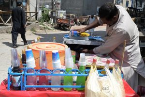 A vendor prepares chilled gola ganda at a roadside cart, as demand for cold and refreshing beverages surges amid the scorching summer heat gripping the city