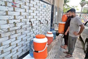 People filling their pots with clean drinking water from filtration plant during hot weather in the Federal Capital.