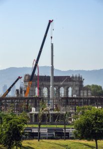 A large crane hoists a towering flagpole into position at the construction site of the "Marka-e-Haq Monument, as work on the grand structure progresses rapidly, with the scenic Margalla Hills forming a striking backdrop.