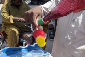 A vendor prepares chilled gola ganda at a roadside cart, as demand for cold and refreshing beverages surges amid the scorching summer heat gripping the city