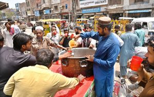 A person is distributing traditional summer drink while arranging "Sabeel" at Muslim Bazaar.