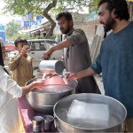 A volunteer serves free chilled drinks to passersby at a roadside stall during hot day at Lehtrar road in the Federal Capital
