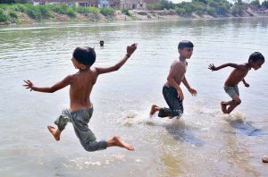 Children enjoy a refreshing swim and playing with water in the Pinyari Canal to escape the scorching summer heat in the city.
