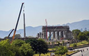 A large crane hoists a towering flagpole into position at the construction site of the "Marka-e-Haq Monument, as work on the grand structure progresses rapidly, with the scenic Margalla Hills forming a striking backdrop.