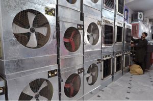 A worker arranges room air coolers on display for sale at a shop in tarlai area, as demand for cooling appliances rises amid the ongoing summer heatwave