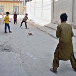 Children are playing the traditional game “Pittu Garam” in a street, enjoying outdoor recreation and preserving local cultural traditions
