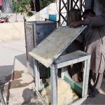 A craftsman repairs a traditional khus (vetiver grass) cooler, at a roadside workshop