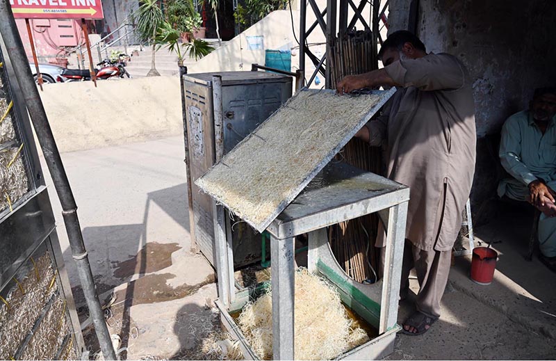 A craftsman repairs a traditional khus (vetiver grass) cooler, at a roadside workshop