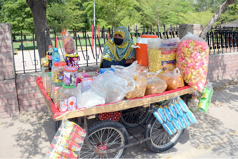 A woman vendor displays a variety of snacks and refreshments on her handcart to attract customers along General Bus Stand Road in the city