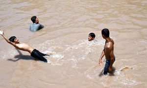 Young boys cool off by bathing in accumulated rainwater beneath the under-construction flyover at Katarian Bridge on I.J.P. Road, seeking relief from the summer heat.