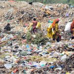 Gypsy women searching valuable items on heap of garbage at Latifabad