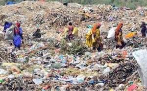 Gypsy women searching valuable items on heap of garbage at Latifabad