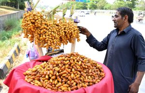 A vendor arranging and displaying fresh dates to attract the customers at his roadside setup.