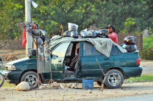 A roadside vendor displays motorcycle helmets and riding accessories on his car to attract customers along the Southern Bypass.