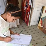 A girl draws a sketch following a step-by-step guide at a stall during the weekly bazaar held at Peshawar Mor, H-9, in the Federal Capital
