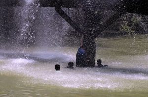 A youngster enjoys bathing in water leaking from a supply line at Channel Mori Canal during hot weather