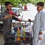 A vendor busy in selling traditional “ice gola” to customer at roadside setup in Federal Capital