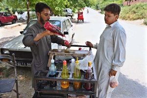 A vendor busy in selling traditional “ice gola” to customer at roadside setup in Federal Capital