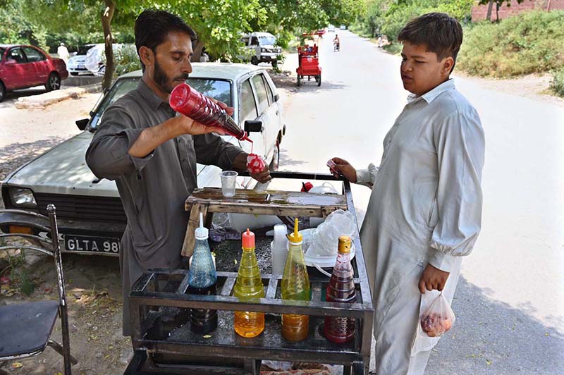 A vendor busy in selling traditional “ice gola” to customer at roadside setup in Federal Capital