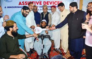 Regional Director DEPD Sindh Imtiaz Ahmad Sheikh and Pakistan Navy Commander Asif Raza present a wheelchair to a woman with disabilities during a wheelchair distribution ceremony at the Vocational Training Centre.