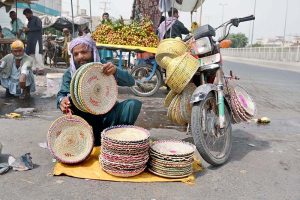 Labourers are loading bundles of brooms onto a loader rickshaw for delivery to local markets for trading and transportation