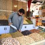 A vendor arranges a variety of dry fruits, including dates, raisins and nuts, on display at his shop weekly bazaar at Peshawar Mor, H-9 in the Federal Capital