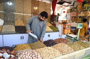 A vendor arranges a variety of dry fruits, including dates, raisins and nuts, on display at his shop weekly bazaar at Peshawar Mor, H-9 in the Federal Capital