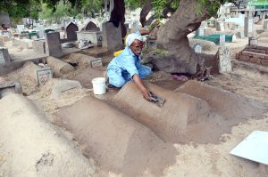 A grave digger repairs and plasters a mud on grave at a local graveyard ahead of Muharram-ul-Haram.