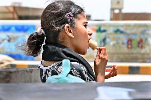 A girl enjoys traditional ice-cream (Kulfi) during hot weather in the city.