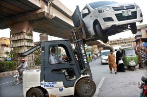 Traffic police wardens remove illegally parked vehicles with the help of lifters during a citywide operation to ensure smooth traffic flow and enforce road safety regulations.